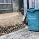 green trash can beside wooden fence